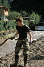 Ein Soldat lenkt das Wasser in die richtigen Bahnen, damit es ungehindert abfließen kann. (Foto: Bundesheer/Rebecca Heindl)