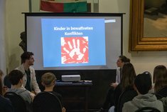 Den Jugendlichen wird eine Präsentation über aktuelle Zahlen von Kindern in Konflikten gezeigt. (Foto: RedTD/Klara Oppenheim)